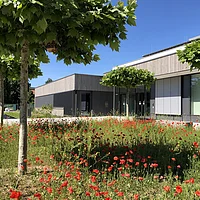 Außenansicht der Altmühltal-Realschule Beilngries von der Seite des Haupteinganges mit Blumenfeld