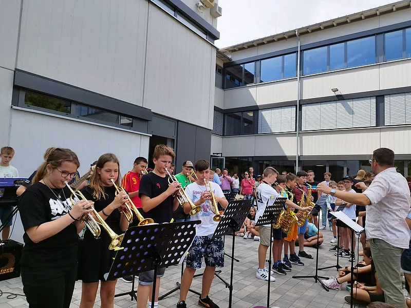 Schülerinnen und Schüler mit Instrumente vor der Schule