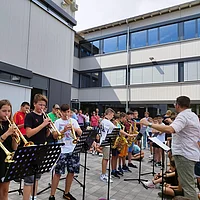 Schülerinnen und Schüler mit Instrumente vor der Schule