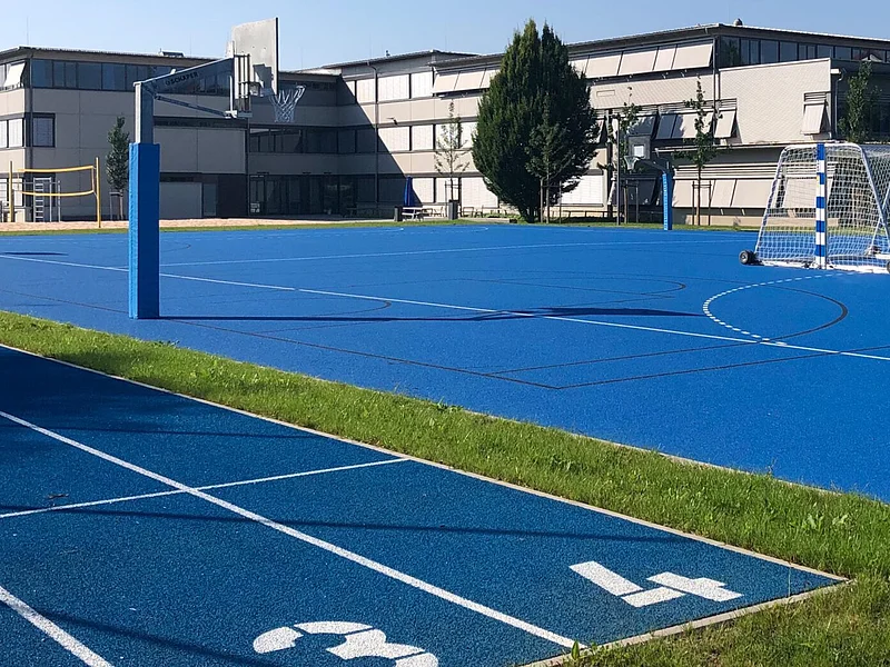 Schulgebäude - Sportplatz Das Bild zeigt das Schulbebäude und den Sportplatz